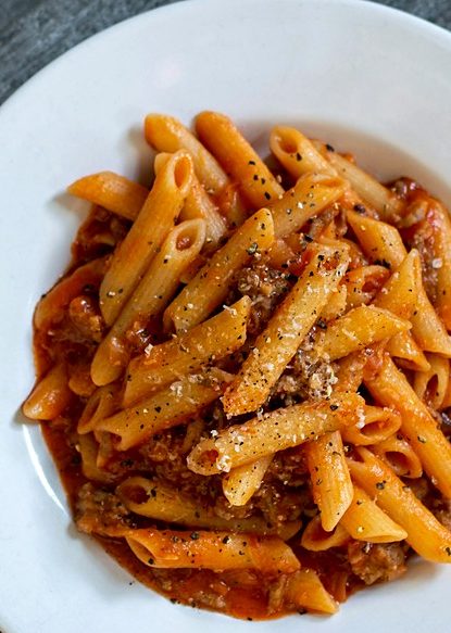 Plate of penne in red sauce finished with grated cheese